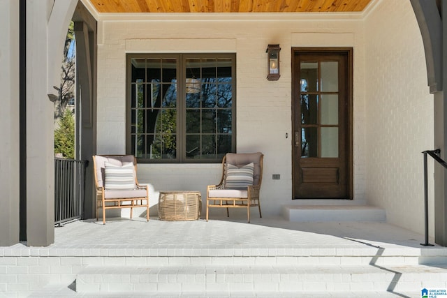 doorway to property featuring a porch and brick siding