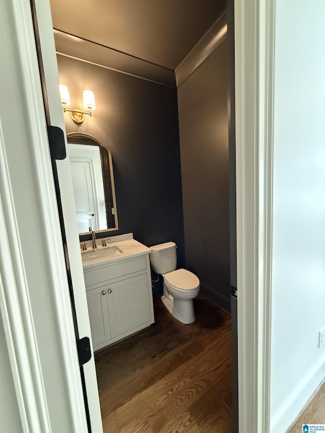 bathroom featuring vanity, hardwood / wood-style flooring, ornamental molding, and toilet