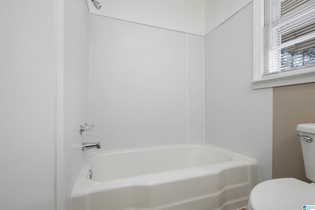 bathroom featuring toilet and a tub to relax in