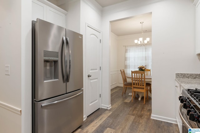 kitchen with light stone countertops, white cabinets, appliances with stainless steel finishes, dark hardwood / wood-style flooring, and an inviting chandelier