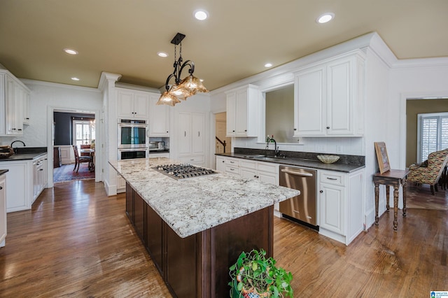 kitchen featuring a kitchen island, dark wood-type flooring, stainless steel appliances, decorative backsplash, and sink