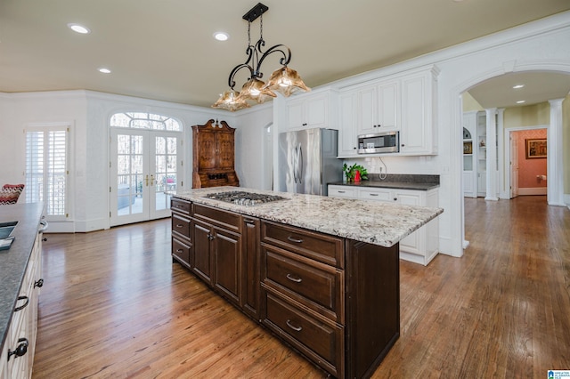 kitchen with dark brown cabinets, a kitchen island, hanging light fixtures, and appliances with stainless steel finishes