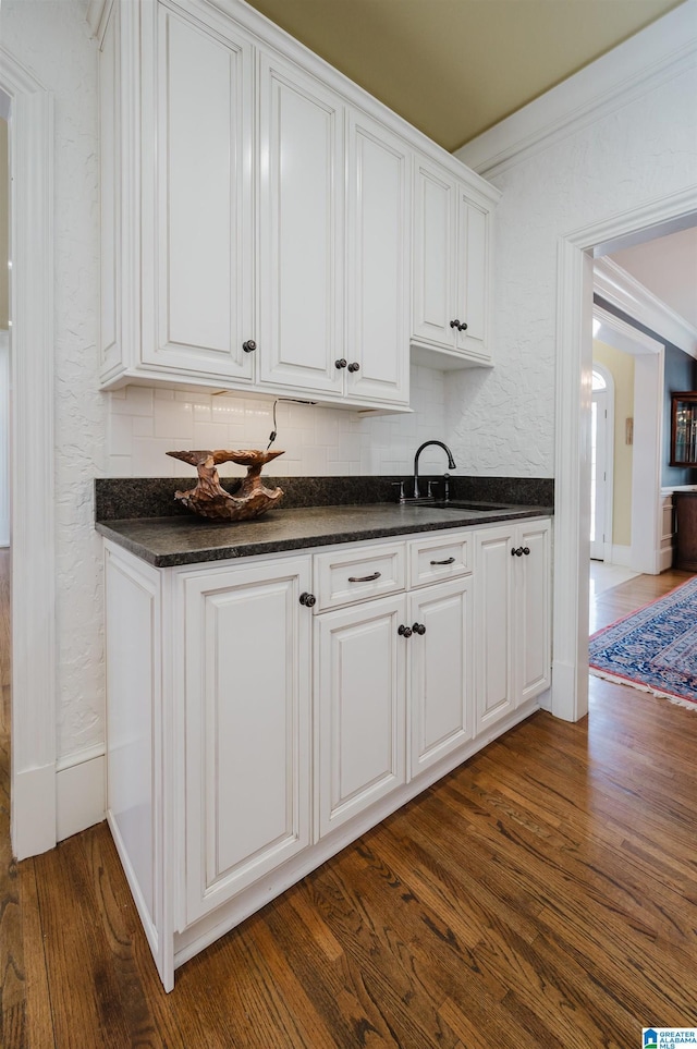 kitchen with sink, white cabinetry, dark hardwood / wood-style flooring, and crown molding