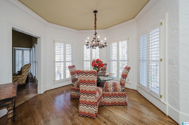 dining space with plenty of natural light, hardwood / wood-style floors, ornamental molding, and a notable chandelier