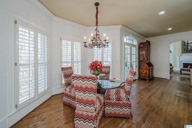 dining area with a chandelier, crown molding, and wood-type flooring