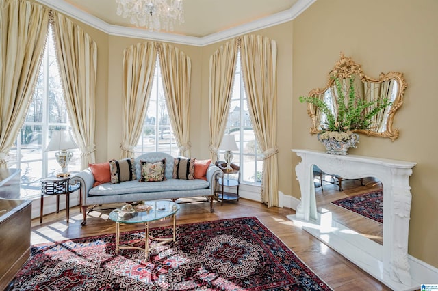 living area featuring ornamental molding, hardwood / wood-style flooring, an inviting chandelier, and plenty of natural light