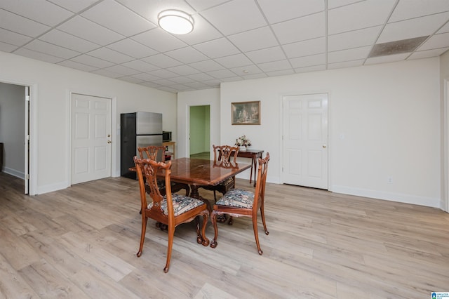 dining room with light hardwood / wood-style floors and a paneled ceiling