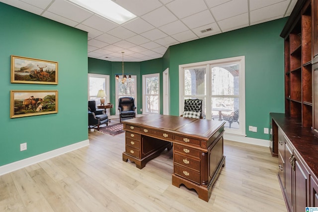 office space with a drop ceiling, light hardwood / wood-style floors, and a chandelier