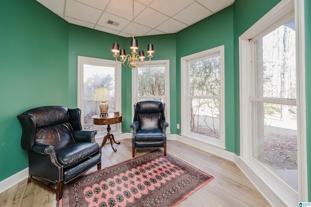 sitting room with hardwood / wood-style flooring, a drop ceiling, and an inviting chandelier