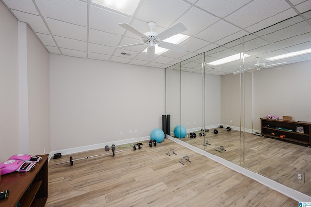 exercise room featuring ceiling fan, wood-type flooring, and a paneled ceiling