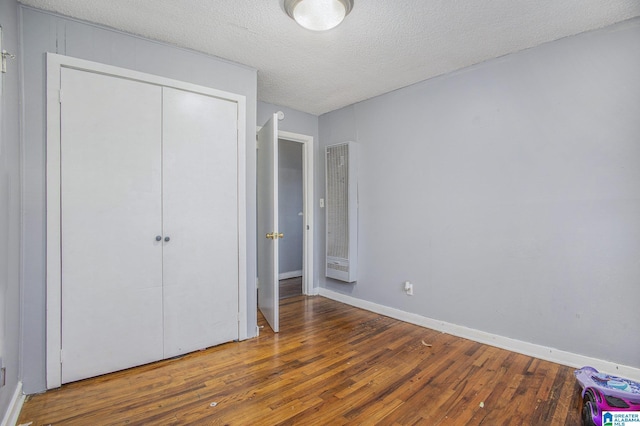 unfurnished bedroom featuring wood-type flooring, a closet, and a textured ceiling