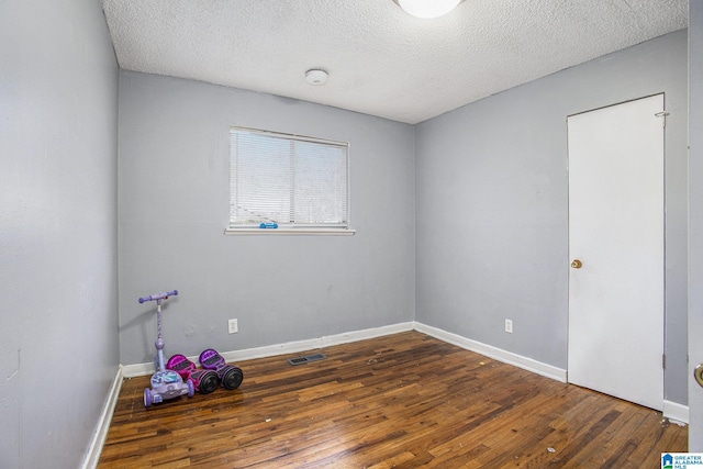 empty room featuring a textured ceiling and dark hardwood / wood-style flooring