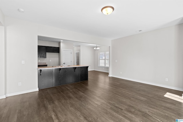 unfurnished living room with a notable chandelier and dark wood-type flooring