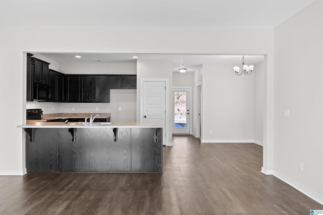 kitchen with black appliances, sink, dark wood-type flooring, and a breakfast bar