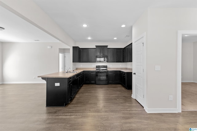 kitchen with wood-type flooring, sink, electric range, kitchen peninsula, and a breakfast bar