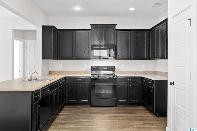 kitchen with sink, dark hardwood / wood-style floors, black appliances, and kitchen peninsula