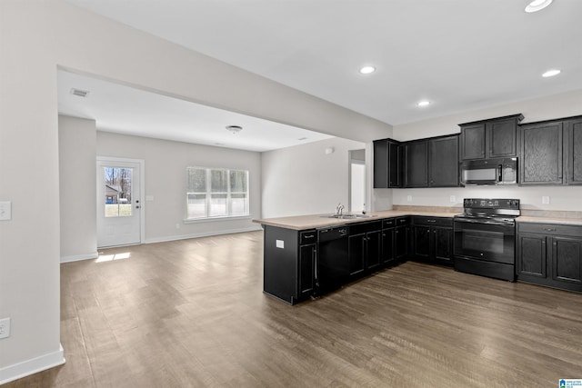 kitchen featuring sink, wood-type flooring, black appliances, and kitchen peninsula