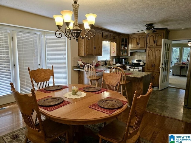 dining space featuring sink, dark hardwood / wood-style flooring, a wealth of natural light, and ceiling fan with notable chandelier