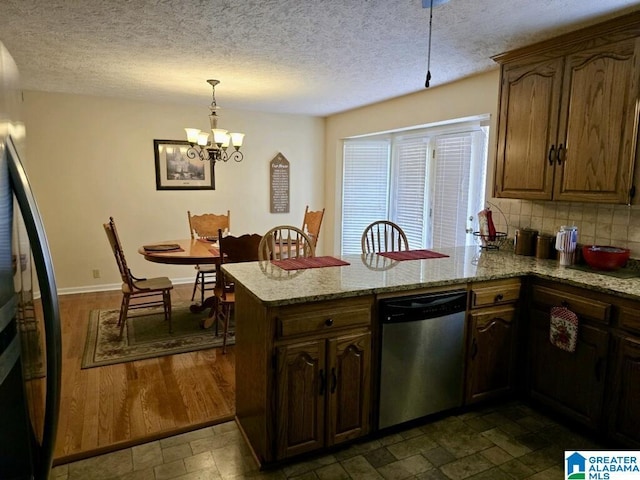 kitchen with stainless steel dishwasher, kitchen peninsula, hanging light fixtures, and light stone counters