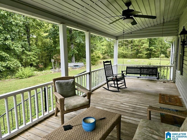 wooden terrace featuring ceiling fan, a porch, and a yard