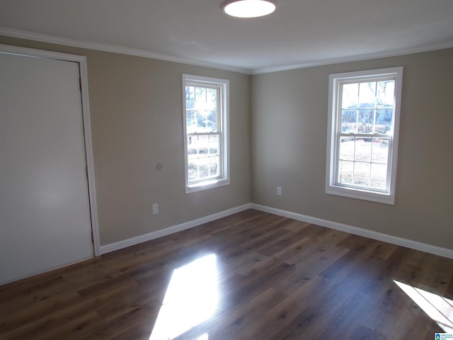 empty room with dark hardwood / wood-style flooring, crown molding, and a healthy amount of sunlight