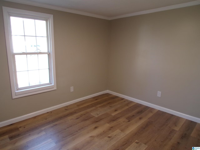 empty room with hardwood / wood-style floors and crown molding