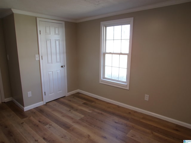 empty room featuring dark wood-type flooring and crown molding