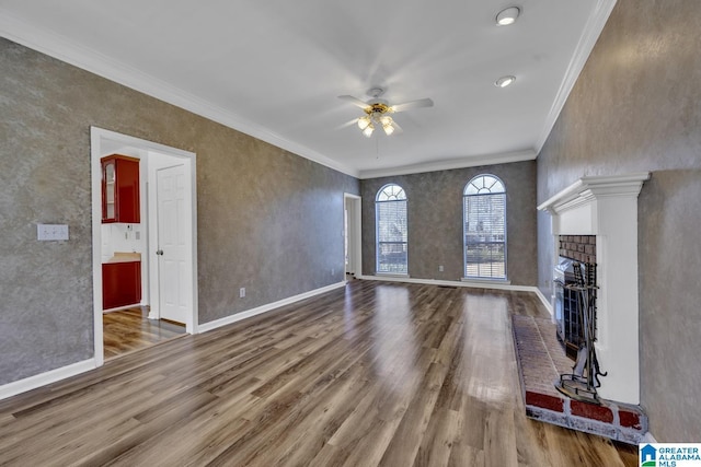 unfurnished living room with hardwood / wood-style flooring, a brick fireplace, crown molding, and ceiling fan