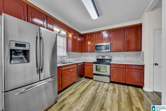 kitchen featuring light wood-type flooring, appliances with stainless steel finishes, tasteful backsplash, and sink