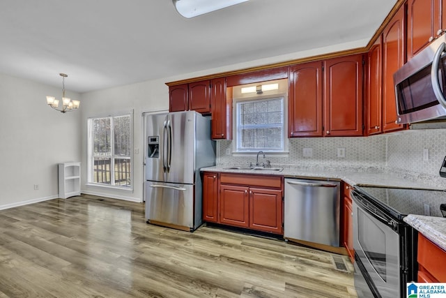 kitchen with pendant lighting, decorative backsplash, sink, light hardwood / wood-style flooring, and stainless steel appliances