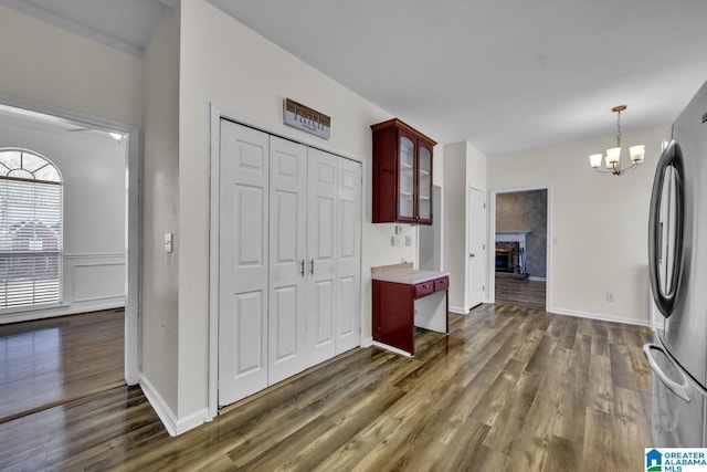 kitchen featuring decorative light fixtures, dark wood-type flooring, a fireplace, an inviting chandelier, and stainless steel fridge