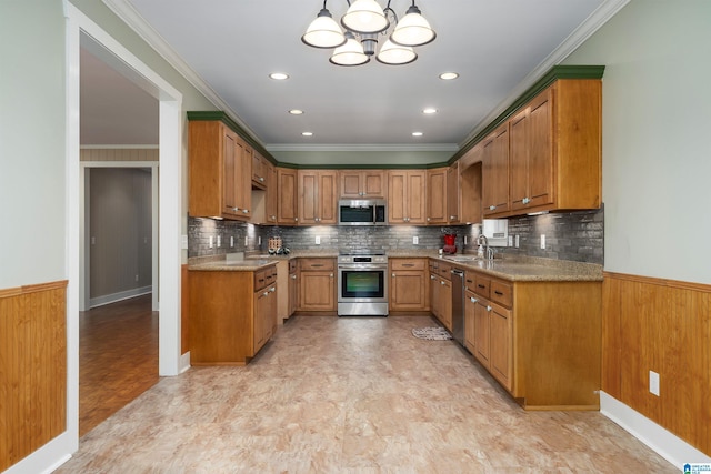 kitchen featuring stainless steel appliances, sink, ornamental molding, and decorative light fixtures