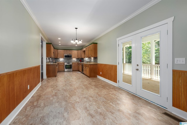 kitchen featuring pendant lighting, appliances with stainless steel finishes, french doors, a chandelier, and crown molding