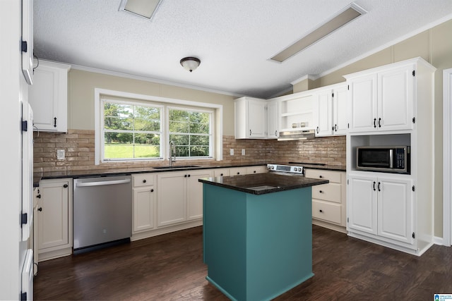 kitchen with white cabinets, appliances with stainless steel finishes, lofted ceiling, a kitchen island, and sink