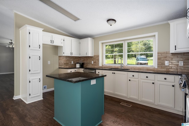 kitchen featuring sink, white cabinetry, a center island, and lofted ceiling