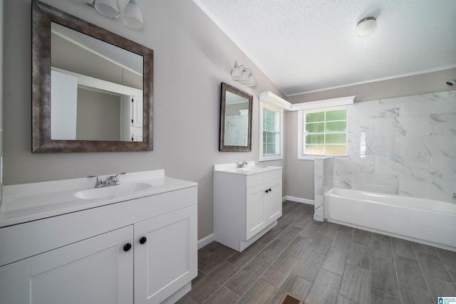 bathroom with a textured ceiling, washtub / shower combination, vanity, and vaulted ceiling