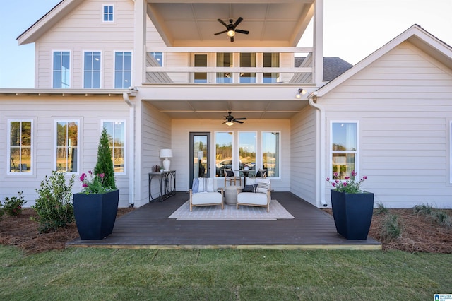 rear view of house featuring a balcony, a deck, a lawn, and ceiling fan