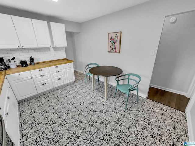 kitchen with tasteful backsplash, butcher block countertops, and white cabinetry