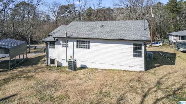 back of house with central AC unit and a yard