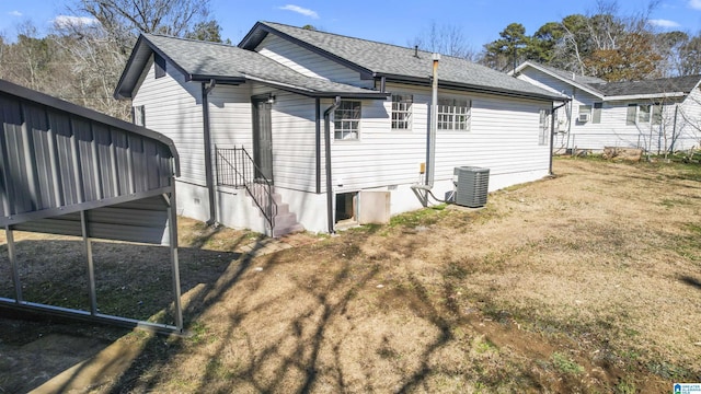 rear view of property with central air condition unit and a yard