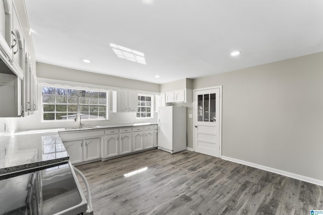 kitchen with hardwood / wood-style floors, white refrigerator, white cabinetry, and sink