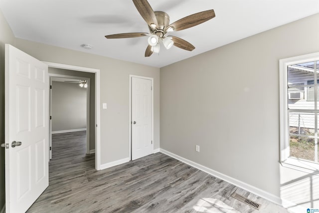 unfurnished bedroom with ceiling fan, a closet, and dark hardwood / wood-style flooring