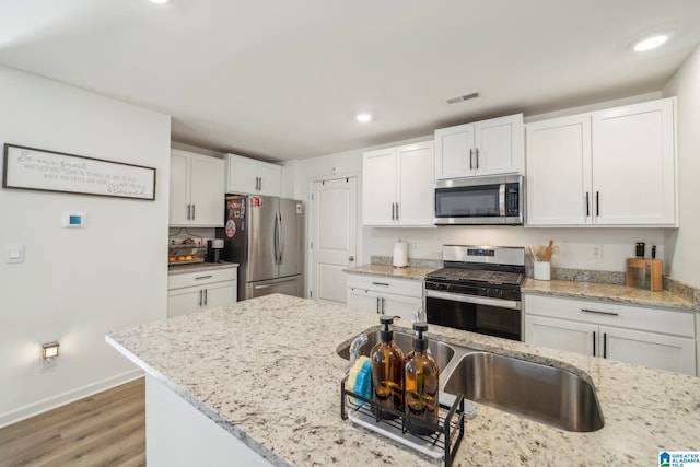 kitchen featuring light stone countertops, white cabinetry, and appliances with stainless steel finishes