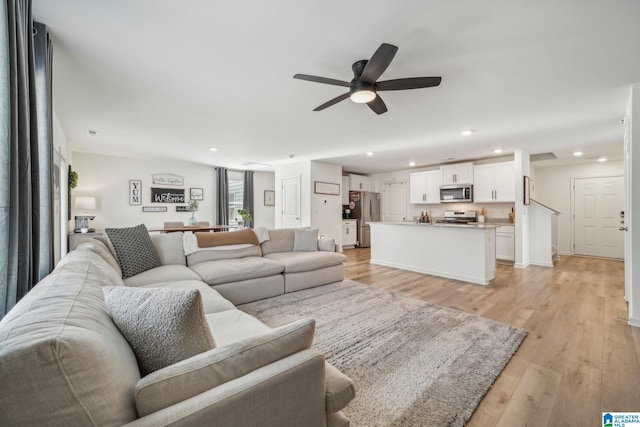 living room with light hardwood / wood-style flooring and ceiling fan