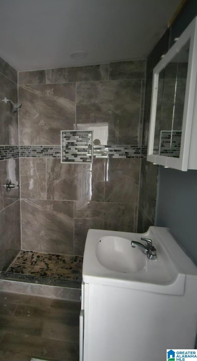 bathroom with tiled shower and vanity