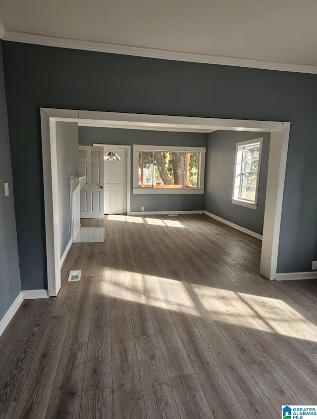 unfurnished living room featuring dark wood-type flooring and crown molding