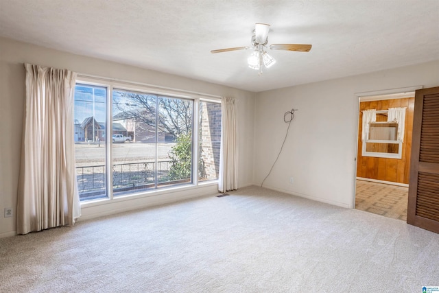 carpeted spare room with a textured ceiling, ceiling fan, and a healthy amount of sunlight