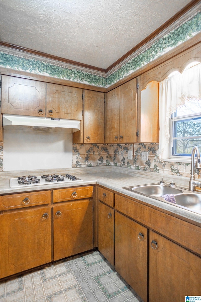 kitchen with a textured ceiling, ornamental molding, white gas cooktop, and sink