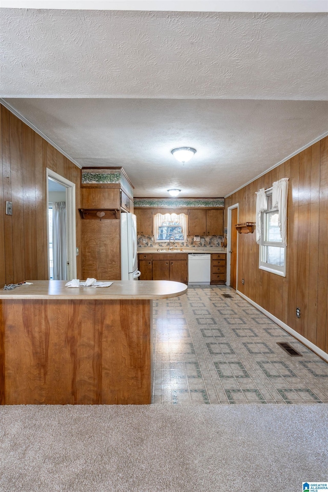 kitchen featuring a textured ceiling, wood walls, and white appliances