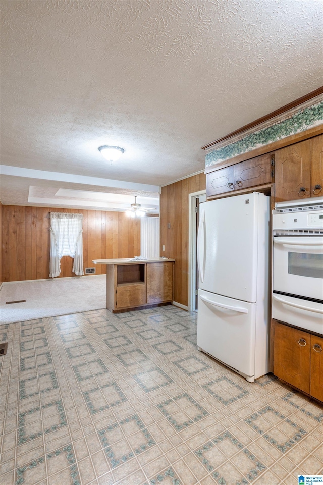 kitchen with a textured ceiling, wooden walls, and white appliances